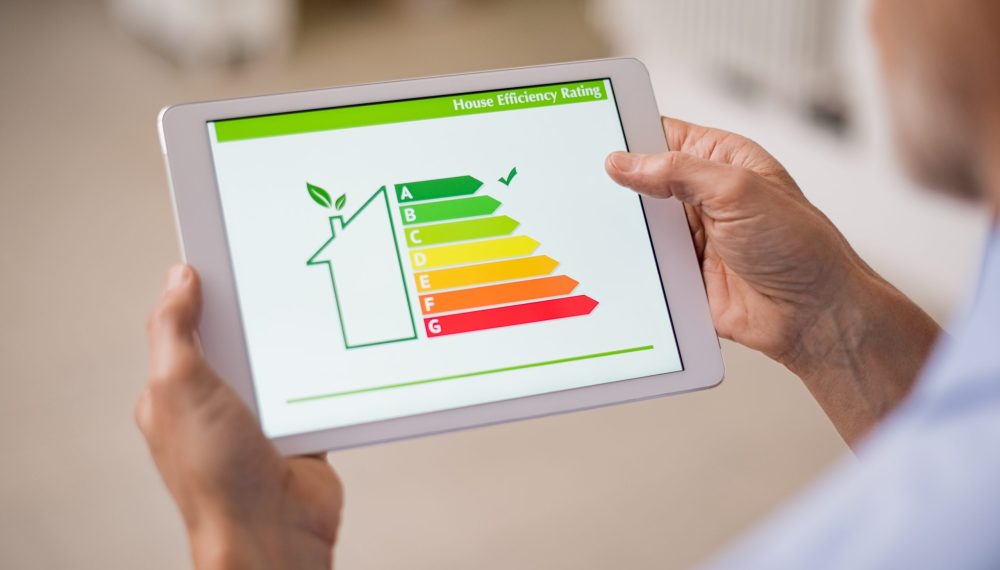 Hand,Holding,Digital,Tablet,And,Looking,At,House,Efficiency,Rating.