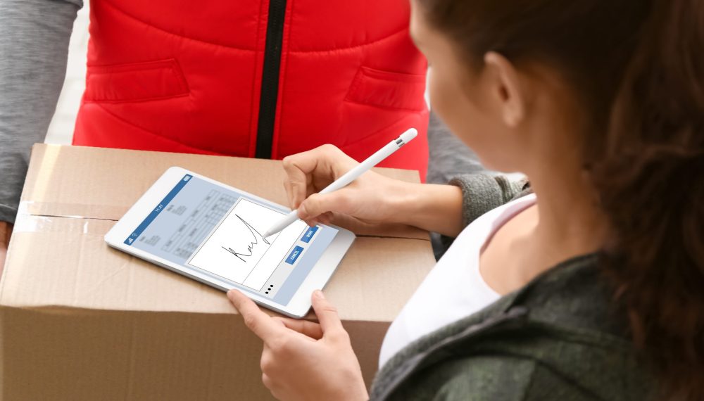 Woman,Appending,Signature,After,Receiving,Parcel,From,Courier,Outdoors