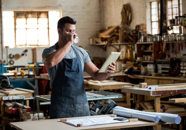 Carpenter,Using,His,Tablet,And,Drinking,A,Coffee,In,A