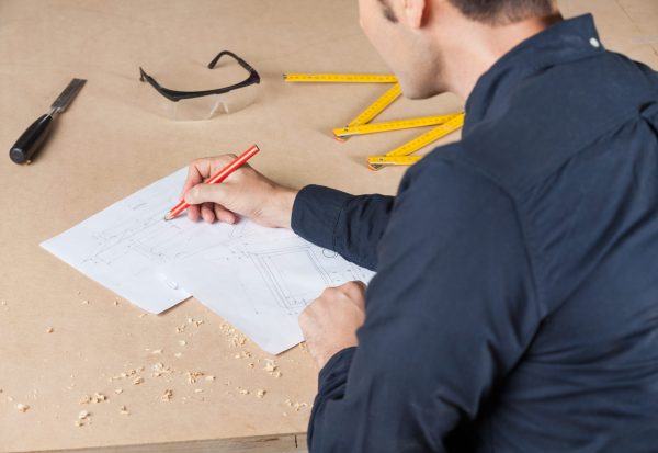 Midsection,Of,Male,Architect,Drawing,Diagram,At,Table,In,Workshop