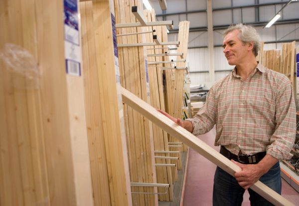 Mature,Man,Selecting,Timber,For,Diy,Project,In,Hardware,Store Woodworker selecting a board from a lumber yard rack for a beginner furniture project