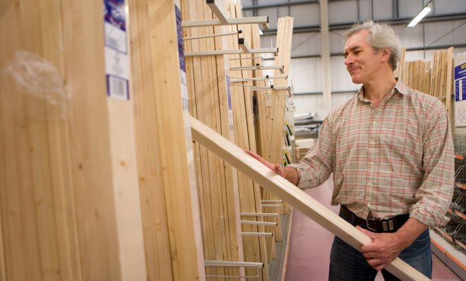 Mature,Man,Selecting,Timber,For,Diy,Project,In,Hardware,Store Woodworker selecting a board from a lumber yard rack for a beginner furniture project