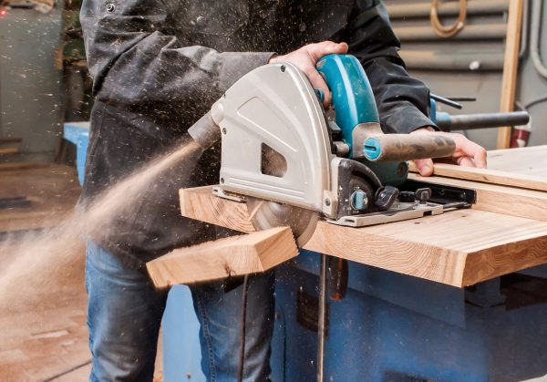 Male,Carpenter,Sawing,A,Board,With,A,Circular,Saw,In