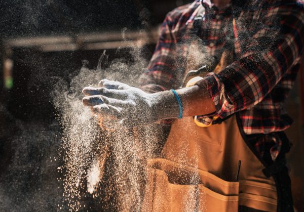 Close,Up,Skilled,African,American,Carpenter,Dusts,Gloves,In,Woodshop