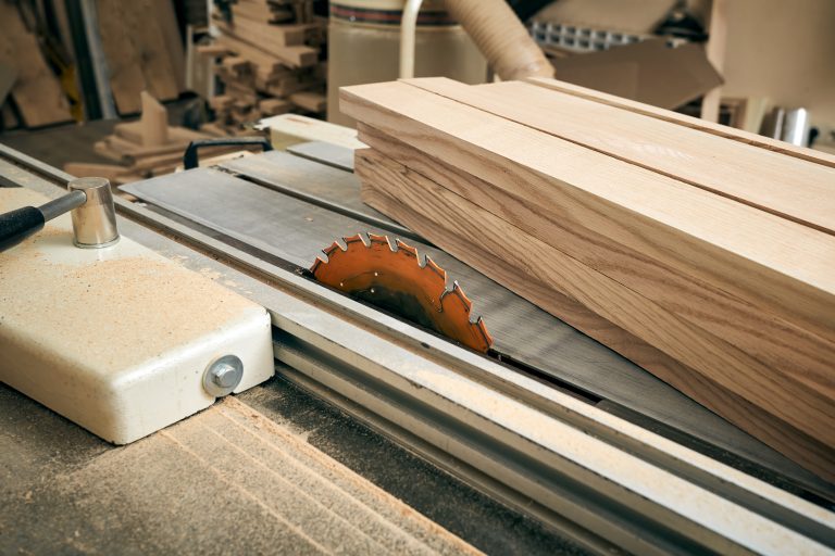 Close-up view of wood boards being cut with a table saw in a workshop