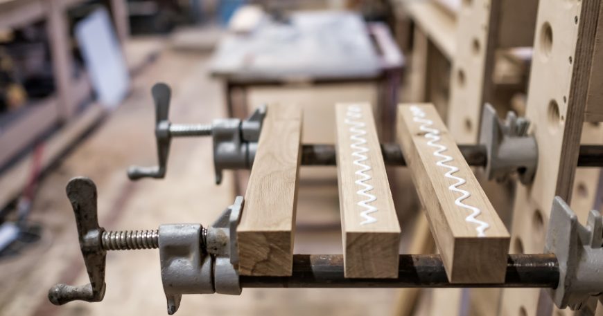 Wood pieces clamped together with visible glue squeeze-out in a garage workshop