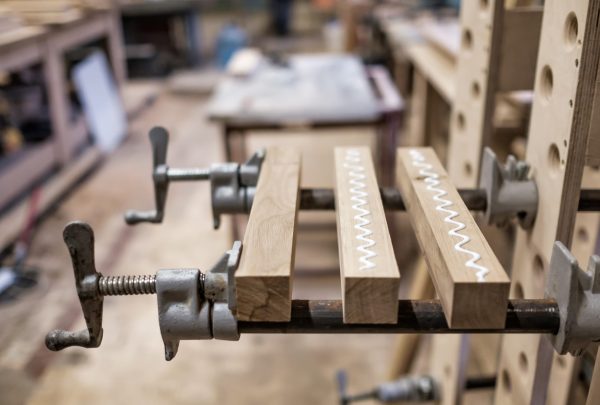 Using,Clamps,And,Glue,To,Connect,Wooden,Timbers,For,Furniture Wood pieces clamped together with visible glue squeeze-out in a garage workshop
