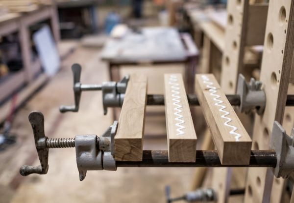 Using,Clamps,And,Glue,To,Connect,Wooden,Timbers,For,Furniture Wood pieces clamped together with visible glue squeeze-out in a garage workshop