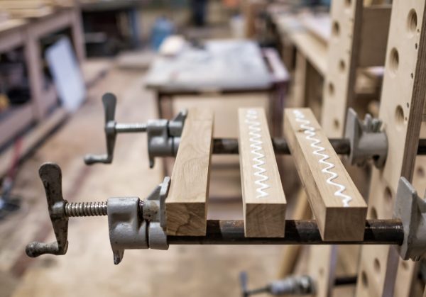 Wood pieces clamped together with visible glue squeeze-out in a garage workshop