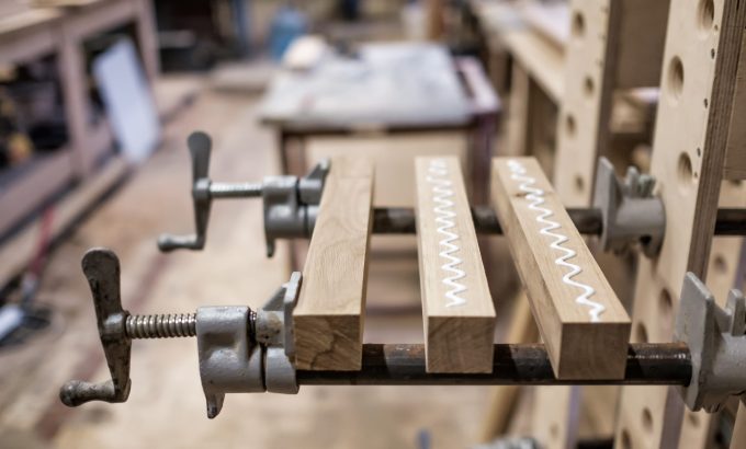 Using,Clamps,And,Glue,To,Connect,Wooden,Timbers,For,Furniture Wood pieces clamped together with visible glue squeeze-out in a garage workshop