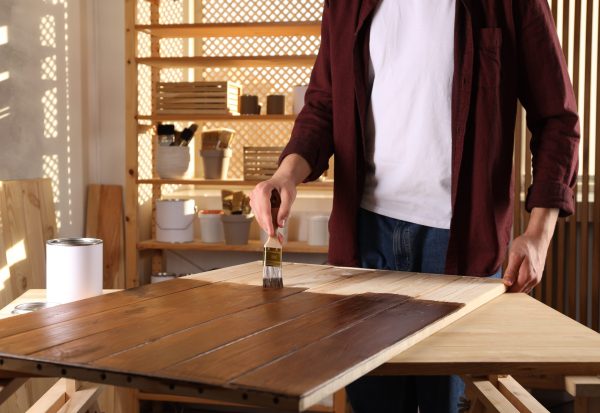 Applying polyurethane finish to a wooden surface with a brush for protection and durability