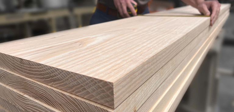 A close-up of stacked oak lumber boards showing clear cathedral arches, useful for identifying wood grain patterns before cutting.