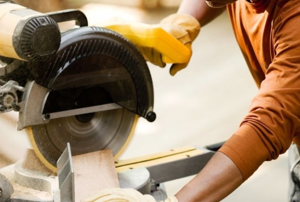 A woodworker making a cut with a power miter saw, highlighting issues when miter saw cuts are not square.