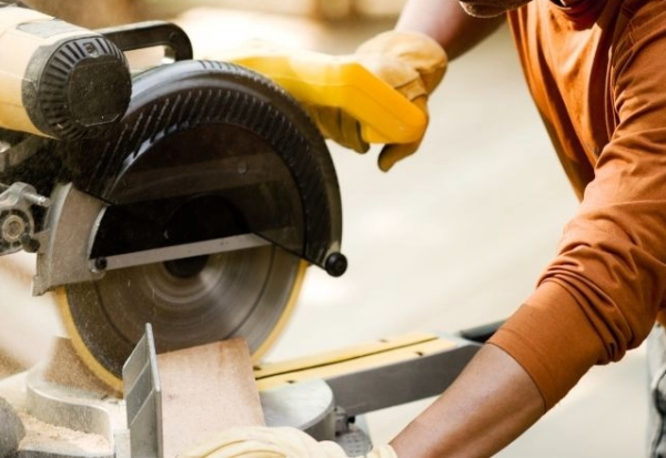 A woodworker making a cut with a power miter saw, highlighting issues when miter saw cuts are not square.