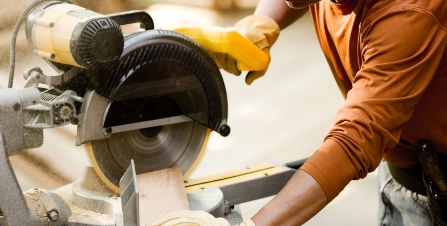 A woodworker making a cut with a power miter saw, highlighting issues when miter saw cuts are not square.